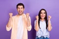 Photo of two delighted overjoyed partners raise fists celebrate isolated on violet color background