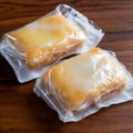 photo of two frozen lemon cookie bars individually wrapped in cling film