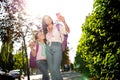 Photo of two funny beautiful sisters carry rucksack hug show v-sign make selfie smart phone sunshine park outdoors Royalty Free Stock Photo