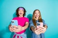 Photo of two funny happy brother and sister takes selfie pictures themselves holding phones smiling isolated on cyan