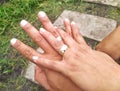 Interlaced hands with engagement rings.