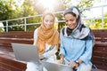 Photo of two islamic girls wearing headscarfs resting in green park