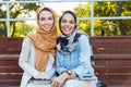 Photo of two islamic women wearing headscarfs sitting in green park