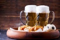 Photo of two mugs of beer and hot dogs on wooden tray with football Royalty Free Stock Photo