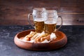 Photo of two mugs of beer and hot dogs on wooden tray