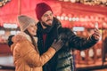 Photo of two people couple students make selfie on x-mas christmas time evening fair noel illumination around outside Royalty Free Stock Photo