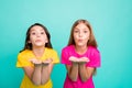 Photo of two playful friendly kind girls wearing colorful pink and yellow t-shirts while isolated with teal background