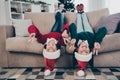 Photo of two positive funky kids lay sofa upside down show v-signs wear jumper hat in decorated home indoors