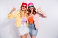 Photo of two pretty ladies raising thumbs up wear sun specs casual clothes isolated white background Royalty Free Stock Photo