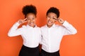 Photo of two young black kids happy positive smile show peace cool v-sign isolated over orange color background Royalty Free Stock Photo