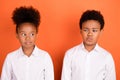 Photo of two young preteen black kids unhappy upset suspicious think isolated over orange color background