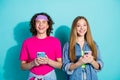 Photo of two young teenage friends hipsters wear old school hipster clothes holding cellphones texting isolated on cyan Royalty Free Stock Photo