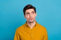 Photo of uncertain handsome guy think look empty space wear yellow shirt isolated blue color background