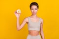 Photo of uncertain lovely lady hold doughnut look think make choice wear grey top isolated yellow color background