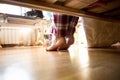 Photo from under the bed on barefoot woman in pajamas