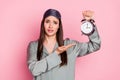 Photo of unhappy irritated young lady sleepwear holding pointing hand arm retro timer isolated pastel pink color