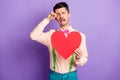 Photo of unhappy lonely young guy wear yellow shirt holding big paper red heart crying tears isolated violet color Royalty Free Stock Photo