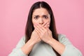 Photo of unhappy scared young woman cover close hands face tell secret isolated on pink color background