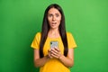 Photo of unhappy scared young woman hold phone dislike reaction addicted blogger isolated on bright green color