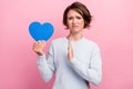 Photo of unhappy upset sad young woman hold blue heart paper shape hand refuse isolated on pink color background