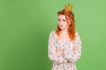 Photo of unhappy upset young offended woman crossed hands look empty space wear crown isolated on green color background