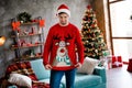 Photo of unsatisfied unpleased young person look reindeer print festive sweater living room house inside