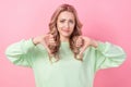 Photo of unsatisfied young person hands fingers demonstrate thumb down isolated on pink color background