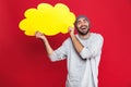 Photo of unshaved man smiling and holding blank thought bubble isolated over red background Royalty Free Stock Photo
