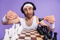 Photo of unsure brunette guy play chess wear spectacles white singlet hairband isolated on lilac color background