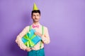 Photo of unsure man dressed yellow shirt birthday headwear holding present looking empty space isolated purple color