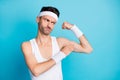 Photo of unsure sporty guy look his hand muscles wear white tank-top singlet isolated over blue color background