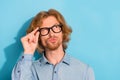 Photo of unsure suspicious young guy dressed jeans shirt arm eyewear looking empty space blue color background