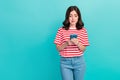 Photo of unsure uncertain girl dressed red t-shirt biting lip reading modern gadget empty space isolated teal color Royalty Free Stock Photo