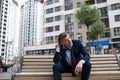 Photo Upset Young Businessman Sitting On Bench. Disappointed businessman sitting on a wooden bench with bottle in his hand in