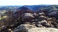 A photo of vegetation being harmed by fire damage, mountain rocks, burnt bushes and a mountain range in the distance Royalty Free Stock Photo