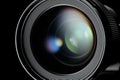 Photo or video camera lens with reflections close-up on the black background