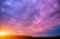 Photo of a violet sunset with clouds and sun Royalty Free Stock Photo