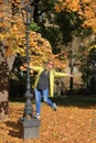 Young cheerful woman dances on the frame of a street lamp in the autumn park Royalty Free Stock Photo