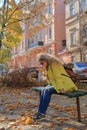 A young woman is resting on a bench in an autumn square