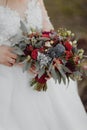 Photo of a wedding bouquet of white different and greenery in the hands of the bride and groom. Royalty Free Stock Photo