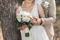 Photo of a wedding bouquet of white flowers and greenery in the hands of the bride and groom. The groom holds the bride's hand. Royalty Free Stock Photo