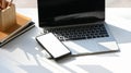 Photo of white blank screen computer laptop putting together with stack of books, mobile and pencil holder. Royalty Free Stock Photo