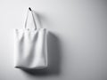 Photo white cotton textile bag hanging left side. Empty concrete wall background. Highly detailed texture, space for