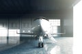 Photo of White Glossy Luxury Generic Design Private Jet parking in hangar airport. Concrete floor. Business Travel