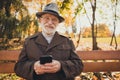 Photo of white hair positive old man english gentleman rest relax autumn october park sunlight sunshine use smartphone Royalty Free Stock Photo