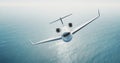 Photo of white luxury generic design private jet flying over the empty sea. Blue sky at background.Business travel Royalty Free Stock Photo