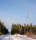 Photo of windmill and straight road in winter forest, blue sky, sunny, Sweden Royalty Free Stock Photo