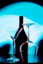 Photo of a wine bottle and two glasses against a light blue stain on a black wall Royalty Free Stock Photo