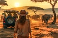 Photo of a woman in a hat approaching a majestic herd of elephants in the wild safary in Africa Royalty Free Stock Photo