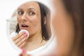 Photo of woman having skin problems looking in the mirror.